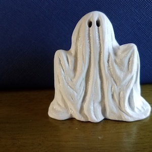 Könnte beinhalten: Weiße Keramik-Geisterfigur mit einem strukturierten, drapierten Laken und zwei schwarzen Augen.