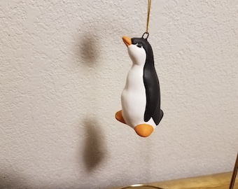 Peut inclure: Ornement de pingouin en céramique, dos noir, ventre blanc, pieds et bec orange. Suspendu par une ficelle dorée, idéal pour les décorations de Noël. Ce pingouin est un ajout charmant à tout arbre de Noël.