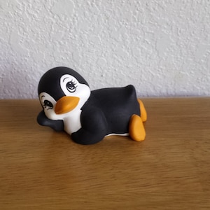 Ceramic Playful Penguin laying down on side resting head on arm(#48D)