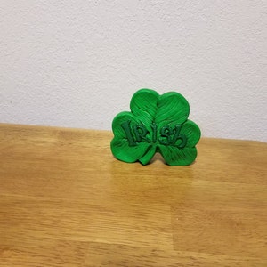 Puede incluir: Un trébol verde con la palabra "Irish" escrita en él.