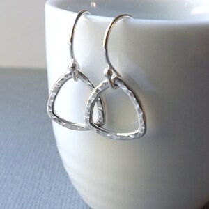 May include: A pair of silver triangle earrings with a hammered texture. The earrings are simple and delicate, and they would make a great gift for a friend or loved one.