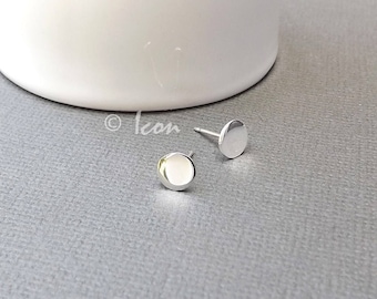 May include: A pair of silver stud earrings with round, flat fronts.