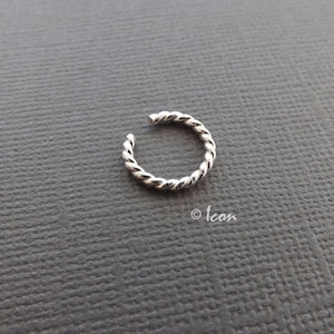 May include: A silver twisted ear cuff. The cuff is made of a single piece of metal that is twisted into a spiral shape.
