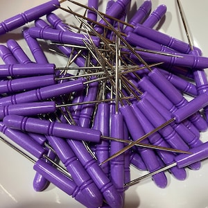 May include: A pile of purple cake decorating tools with metal skewers and plastic handles.
