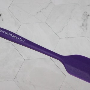 May include: Purple silicone spatula with a white handle that says "Truly Mad Plastics LLC".