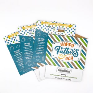 May include: A blue and green gift box with the words "Happy Father's Day" on the front. The box has a handle and is decorated with white polka dots. The box includes four blue cards with the text "Top 10 Dad Phrases" and a list of humorous phrases.
