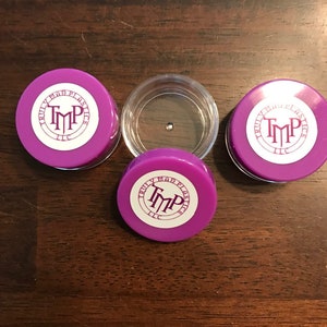 May include: Three purple plastic containers with white labels that say "Truly Mad Plastics, LLC" and a logo of the letters "TMP" in a circle.