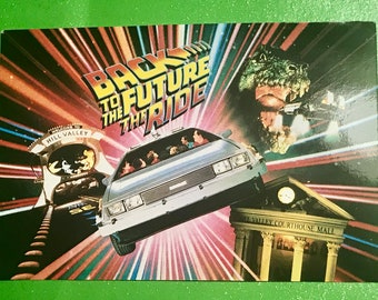 May include: A vintage postcard featuring a colorful illustration of the Back to the Future ride at Universal Studios. The image includes the DeLorean time machine, the clock tower from the movie, and the text "Back to the Future the Ride".