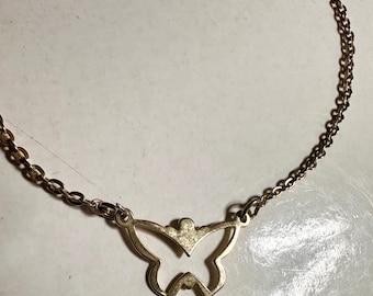 May include: A gold-colored necklace featuring a butterfly pendant. The butterfly pendant is a cutout design, with the chain attached to the top corners of the butterfly's wings. The necklace is displayed on a white surface.