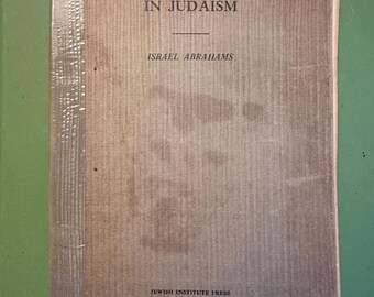 May include: A vintage book titled "Permanent Values in Judaism" by Israel Abrahams. The cover is a faded brown with the title and author's name in black text. The book is published by Jewish Institute Press.