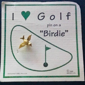 May include: A white card with green trim features a golf course with a gold bird pin on a green flag. The card reads "I ♥ Golf pin on a "Birdie""