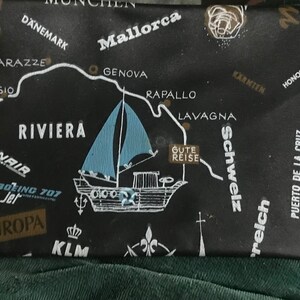 Puede incluir: Tela de temática de viaje en blanco y negro con un mapa de Europa, un velero y un edificio. La tela tiene texto en varios idiomas, incluyendo "Mallorca", "Spanien", "Genova", "Riviera", "Schweiz", "Puerto de la Cruz", "Stockholm", "Wunderwelt", "Finnair", "Touropa", "KLM" y "Boeing 707 Jet".