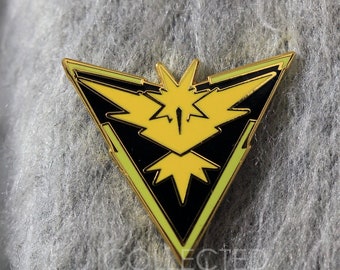 May include: A yellow and black enamel pin featuring the Pokemon character,  Articuno, in a triangular shape with a lightning bolt design.