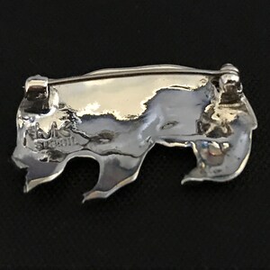 Op de afbeelding: Zilveren broche met een textuur, abstract ontwerp. De achterkant van de broche heeft een pin en sluiting en de inscriptie "MK Sterling".
