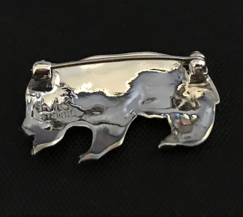Op de afbeelding: Zilveren broche met een textuur, abstract ontwerp. De achterkant van de broche heeft een pin en sluiting en de inscriptie "MK Sterling".