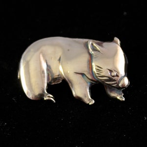 Op de afbeelding: Een zilverkleurige broche in de vorm van een wombat. De wombat wordt afgebeeld in een wandelende houding, met zijn kop naar de zijkant gedraaid. De broche is gedetailleerd met een getextureerd oppervlak en een realistische weergave van de kenmerken van de wombat.