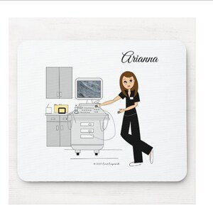 May include: A white background with a cartoon illustration of a woman in a black uniform operating an ultrasound machine. The woman has brown hair and is smiling. The text "Arianna" is written in black cursive at the top of the image.