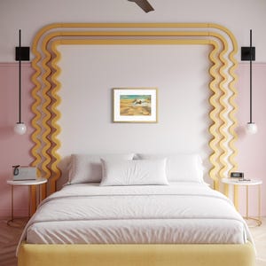 May include: A bedroom with a yellow bed frame and headboard, white bedding, and a framed artwork. The walls are pink and white, with a yellow decorative element. Black ceiling fan and sconces complete the decor.
