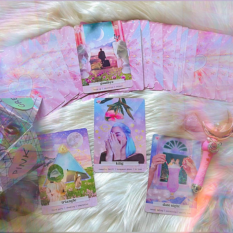 May include: A set of pink and white oracle cards with illustrations and text. The cards include "goodbye", "kilig", "triangle", and "date night".