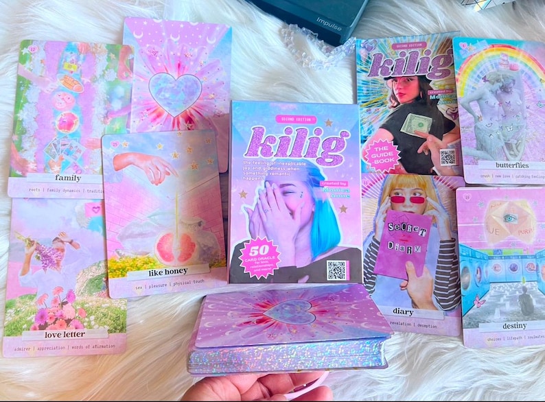May include: A set of 50 oracle cards with a pink and purple color scheme. The cards feature illustrations of butterflies, hearts, and other whimsical imagery. The cards are titled "Kilig: The Guide Book".
