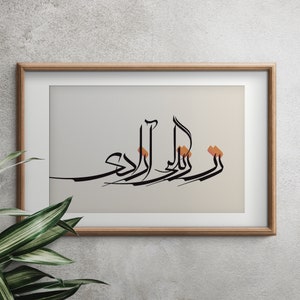 May include: A framed print of Arabic calligraphy in black ink on a light gray background. The calligraphy is in a decorative style with some of the letters highlighted in orange.
