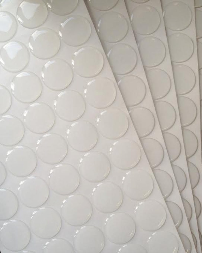 May include: A sheet of clear, round adhesive stickers on a white background. The stickers are arranged in rows and columns.