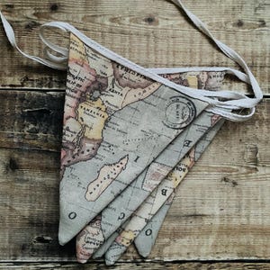 May include: A set of fabric pennants with a vintage world map design. The pennants are beige with brown, yellow, and red accents. The map features the continents of Africa and Australia. The pennants are strung together with white string.