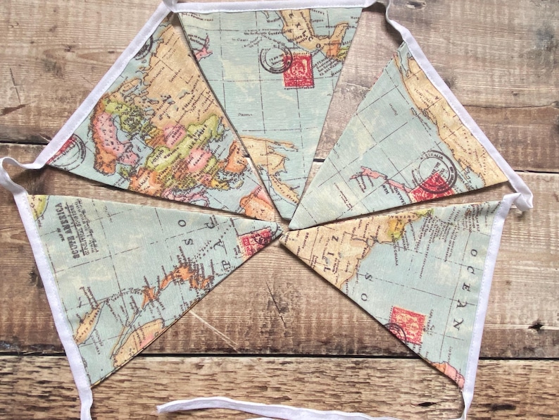 May include: A blue and beige fabric bunting with a world map design. Each flag has a white border and features a vintage-style map with red and yellow accents. The bunting is perfect for a travel-themed party or nursery.