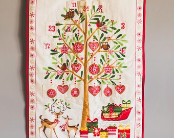 May include: A festive Christmas advent calendar with a tree design. The cream-colored fabric features a brown tree with red ornaments, birds, and owls. The calendar includes pockets numbered 1-24, with a reindeer and sleigh at the bottom.