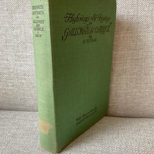 Könnte beinhalten: Ein grünes Vintage-Buch mit dem Titel "Highways & Byways in Galloway & Carrick" von C.H. Dick. Der Buchrücken zeigt den Titel und den Namen des Autors. Das Buch hat ein leicht verblasstes Aussehen.