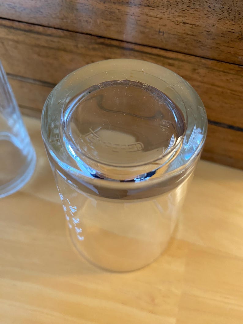Op de afbeelding: Transparante glazen tumbler met een dikke bodem en een licht uitlopende rand. Het glas heeft een glad, transparant uiterlijk, met ge&euml;tste markeringen langs de zijkant. De bodem van het glas heeft de tekst "TEMPERED".