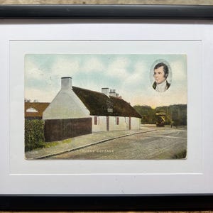 May include: Framed vintage postcard print of Burns Cottage, a historic building with a thatched roof and white walls. The image includes a portrait of a man and the text "BURNS' COTTAGE". The frame is black.