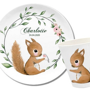Könnte beinhalten: Ein weißes Keramik-Set aus Teller und Tasse mit einer Aquarell-Illustration eines Eichhörnchens und eines Vogels. Der Teller hat einen grünen Blätterkranz mit dem Namen Charlotte und dem Datum 24.04.2020.