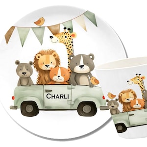 Op de afbeelding: Een wit keramiek bord met een kleurrijke illustratie van dieren die in een groene vrachtwagen rijden. De vrachtwagen heeft de naam "CHARLI" aan de zijkant. De dieren zijn een giraffe, een leeuw, een beer en een aap. Het bord is versierd met een groen-witte vlaggenlijn.