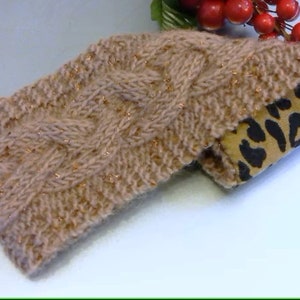 May include: A knitted headband with a cable knit pattern in a light brown color with gold flecks. The headband is lined with a brown fabric with a leopard print.