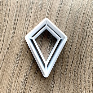 May include: White plastic diamond-shaped cookie cutter with three layers.