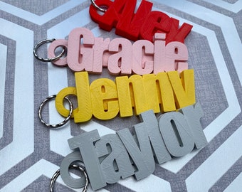 May include: Four colorful keychains with the names Alex, Gracie, Jemmy, and Taylor printed on them. Each keychain has a silver metal ring.