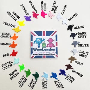 May include: A collection of colorful robot-shaped charms in various shades, including neon pink, yellow, and blue, arranged around a square card with a robot design and the text "WowLondon".