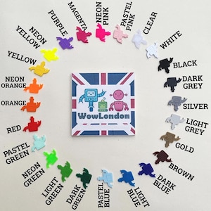 May include: A collection of colorful robot-shaped embellishments in various shades, including neon pink, yellow, and green, arranged around a square graphic with the text "WowLondon" and a Union Jack design. The embellishments are in a variety of colors.