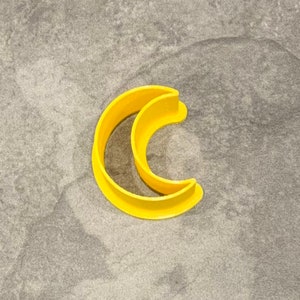Pode incluir: Um cortador de biscoitos de lua crescente de plástico amarelo.