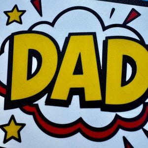 May include: A comic book style graphic with the word "DAD" in large yellow letters outlined in black. The background is white with a blue cloud shape behind the word, and red and yellow starburst accents.