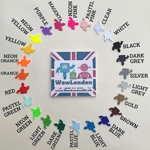 Puede incluir: Una carta de colores con peque&ntilde;os dijes en forma de robot en varios colores, incluyendo rosa ne&oacute;n, morado y azul claro. El logotipo y la direcci&oacute;n del sitio web de WowLondon est&aacute;n incluidos.
