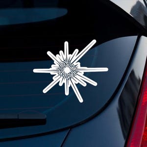 Puede incluir: Una calcomanía de vinilo blanca con un diseño de estallido estelar estilizado con patrones de circuitos complejos que irradian desde un punto central circular, aplicada sobre el cristal oscuro de la ventana trasera de un vehículo.