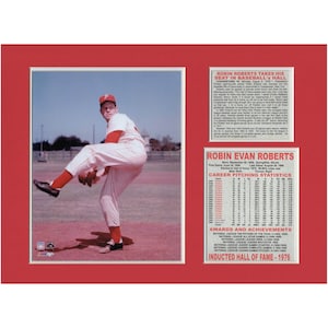 May include: A vintage photo of baseball pitcher Robin Roberts in his Phillies uniform, throwing a pitch. The photo is framed with a red mat and includes text about Roberts' career and induction into the Baseball Hall of Fame.