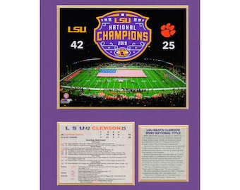 May include: A framed print commemorating the 2019 College Football Playoff National Championship game between LSU and Clemson. The image features the LSU Tigers defeating the Clemson Tigers 42-25. The print includes a photograph of the game, a scorecard, and a news article about the game.