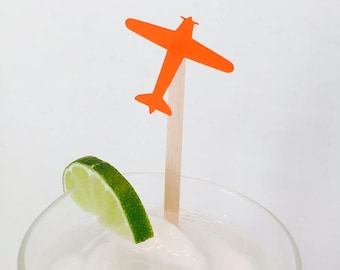 May include: A glass of ice water with a lime wedge and a small orange airplane-shaped paper party pick.
