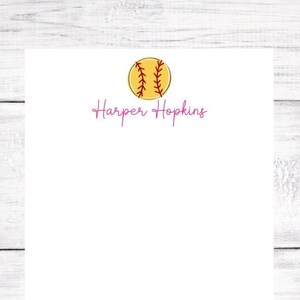 May include: A white notepad with a yellow softball and the text "Harper Hopkins" in pink.