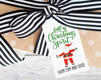 May include: A white gift tag with green text that reads "full of Christmas spirit". A cartoon Santa Claus is illustrated on the tag. The text "From Tom and Susie" is at the bottom of the tag.