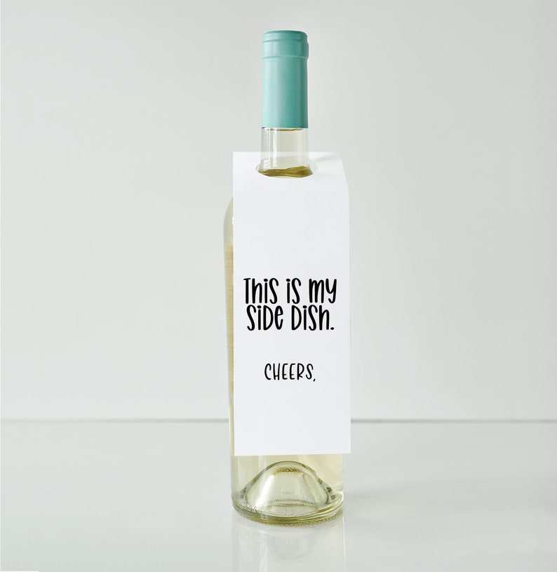 May include: White wine bottle with a white paper gift tag that says "This is my side dish. Cheers."