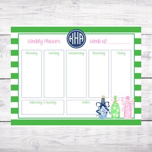 May include: A weekly planner with a green and white striped background. The planner has sections for each day of the week, as well as a notes section. The planner also features a monogram in the top centre.